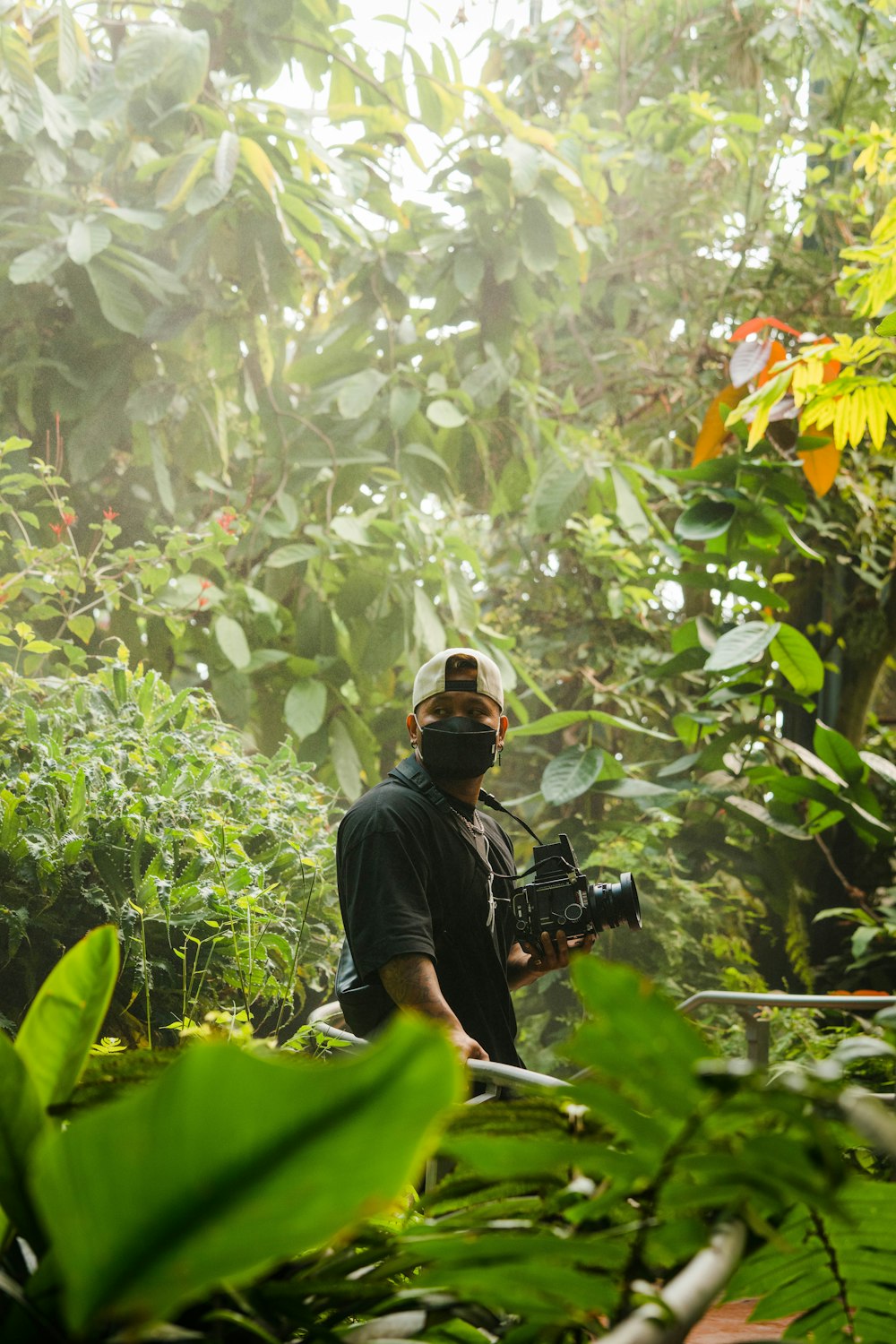 a man holding a camera in the middle of a jungle