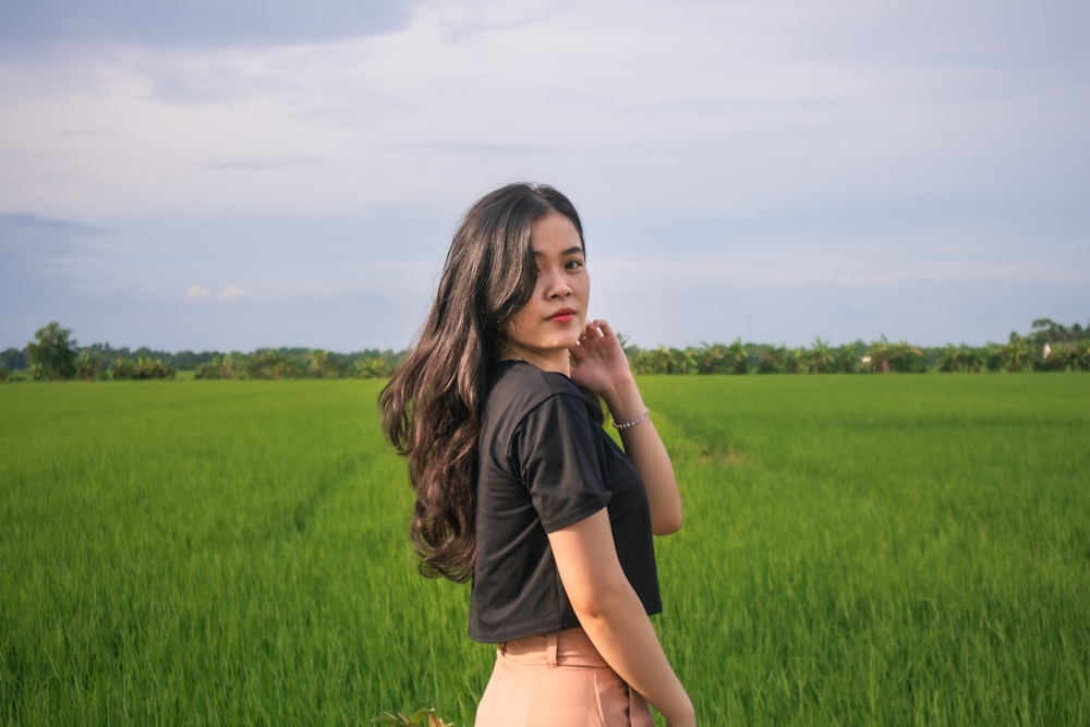 a woman standing in front of a green field