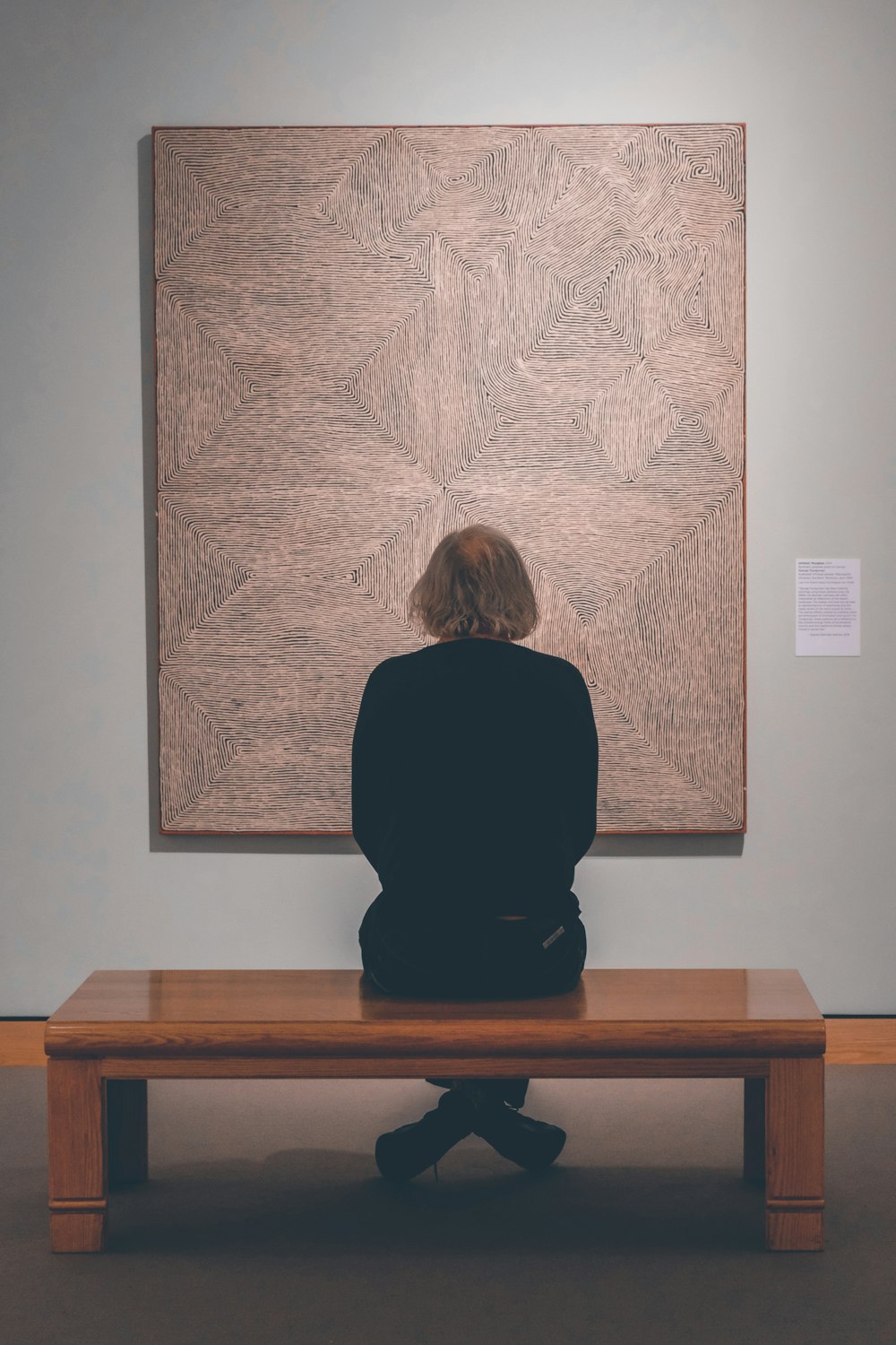 a person sitting on a bench in front of a painting