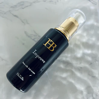 Elegant hair treatment serum bottle surrounded by natural ingredients like argan oil and herbs.