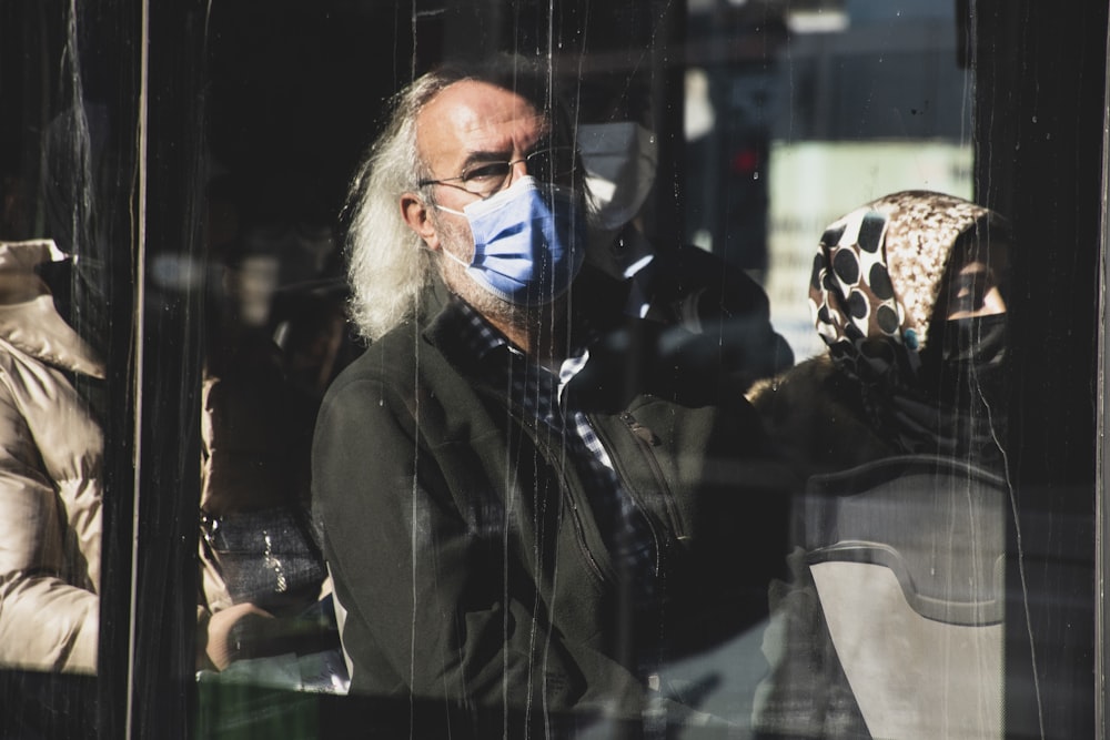 Un uomo che indossa una maschera facciale che guarda fuori da una finestra