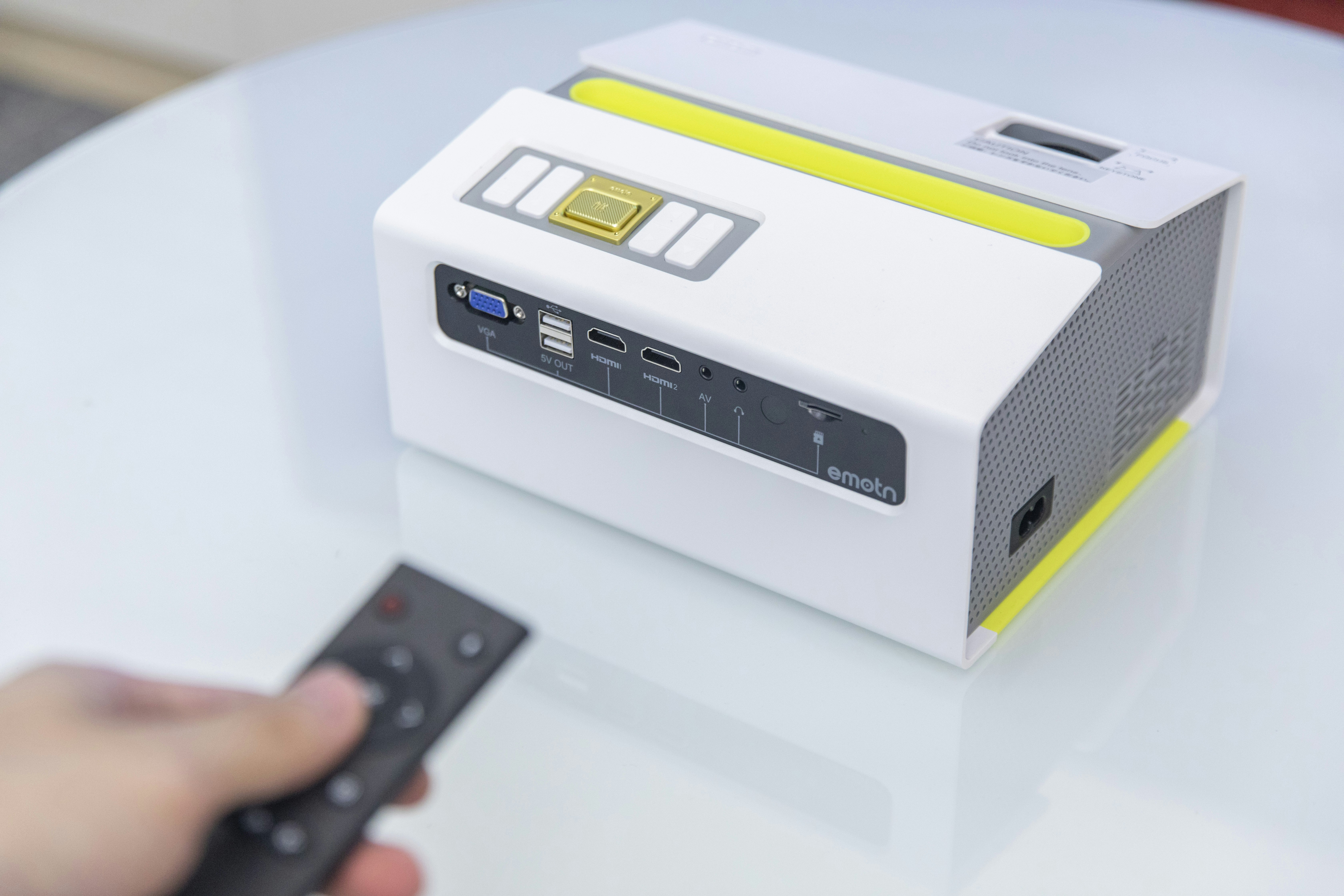 a person holding a remote control in their hand, Emotn C1 is a fashionable and portable projector</p><p>Portable projector/ LCD projector/ LED projector /720P projector</p><p>https://www.projector1.com/