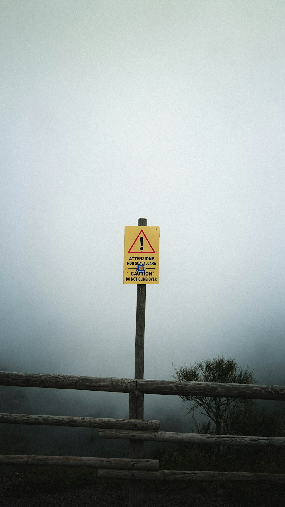 a warning sign on a wooden fence on a foggy day