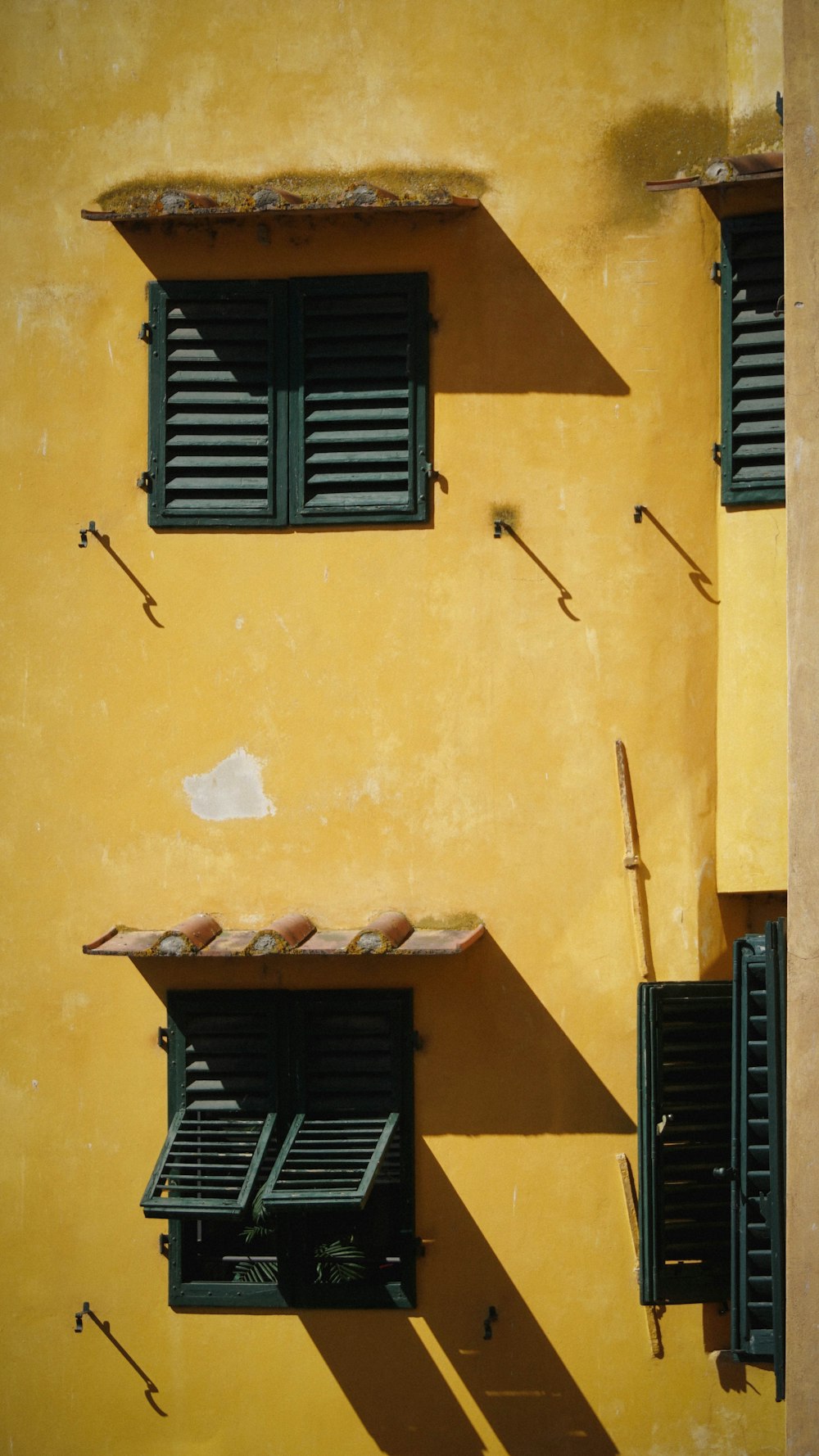 a yellow building with two windows and shutters