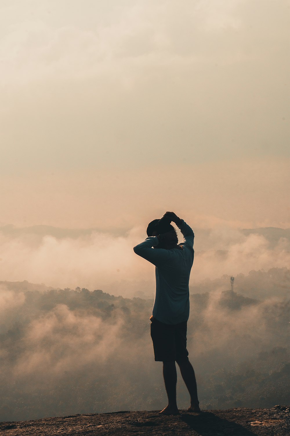 a man standing on top of a mountain looking at the clouds