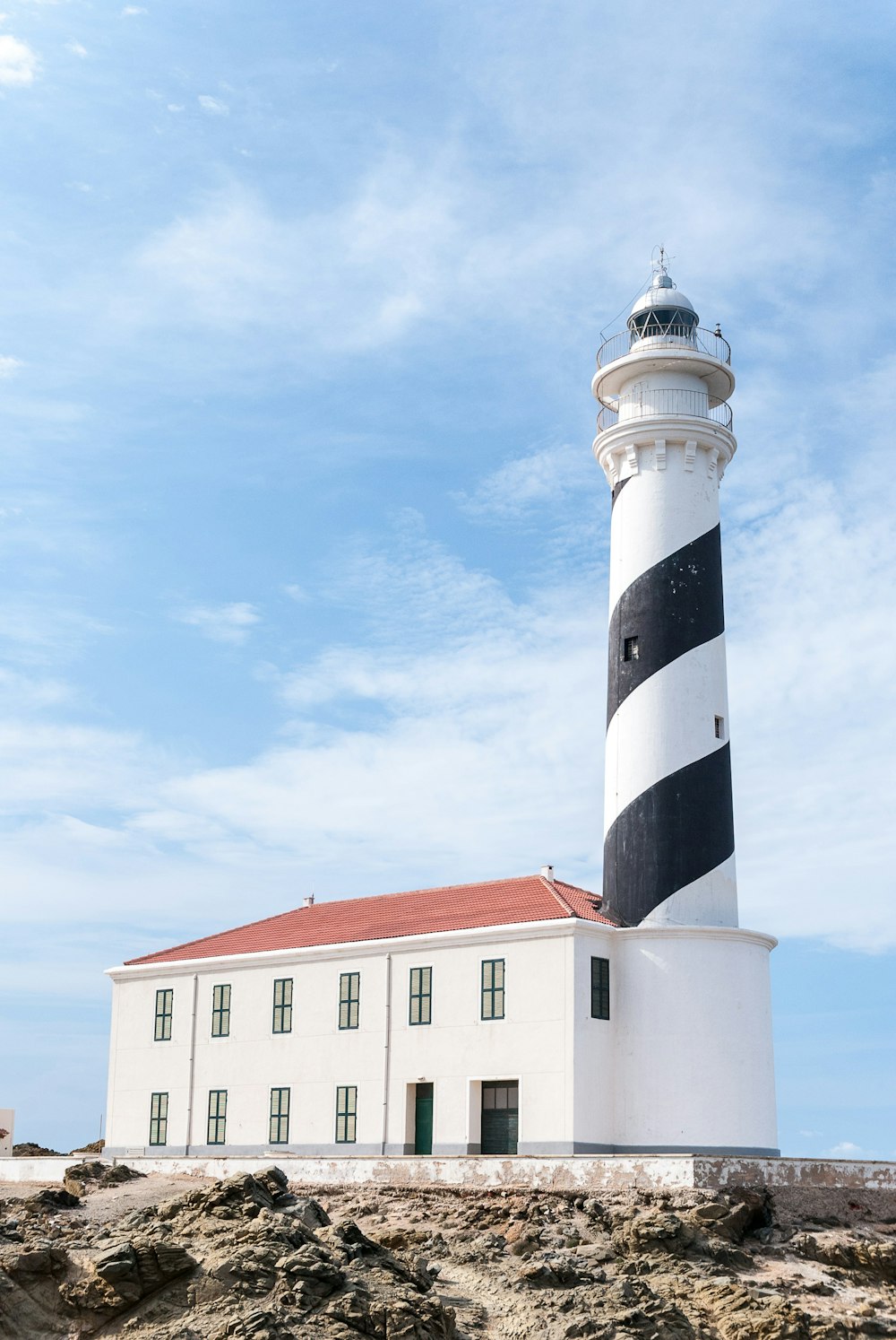a white and black lighthouse with a red roof