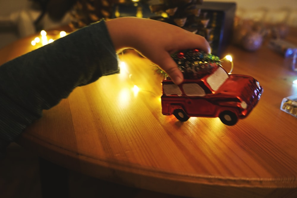 a child's hand reaching for a toy car on a table