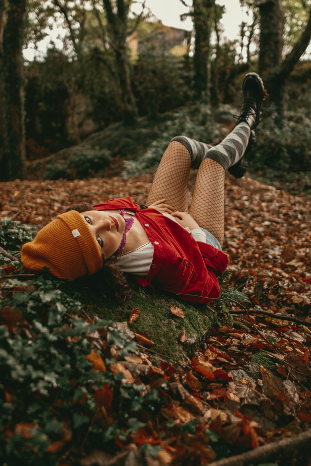 a woman laying on the ground in a forest