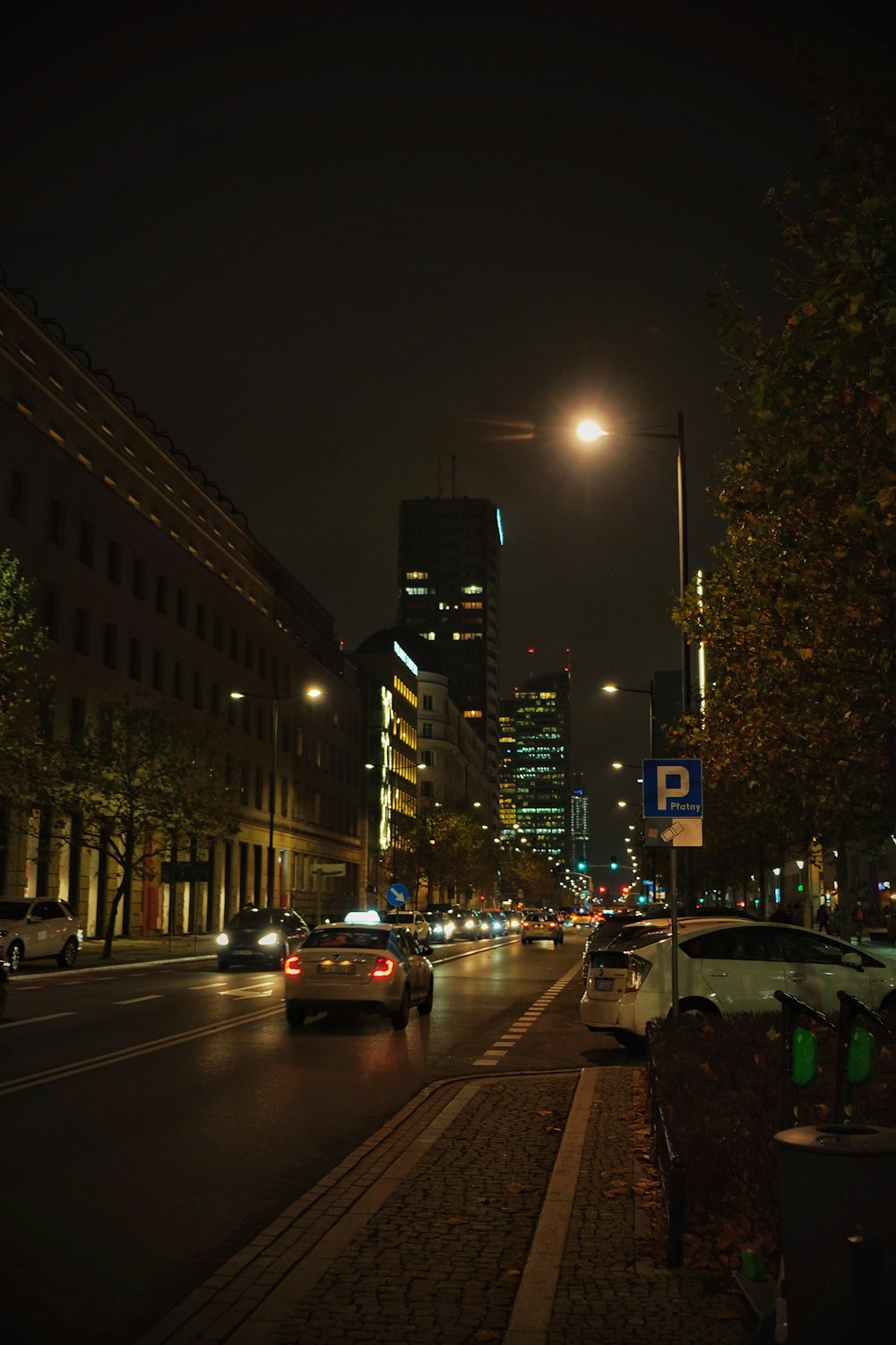 a city street at night with cars driving down it
