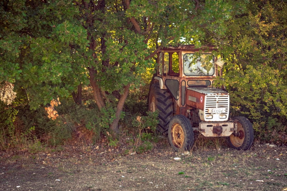 an old tractor sitting in the middle of a forest