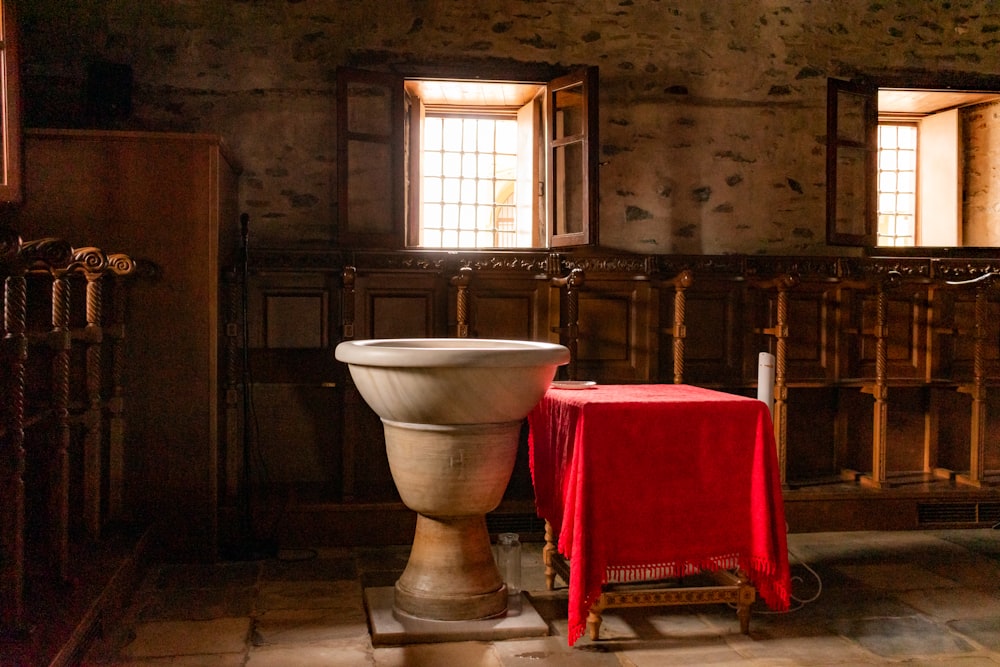 a large urn sitting in a room next to a red table cloth