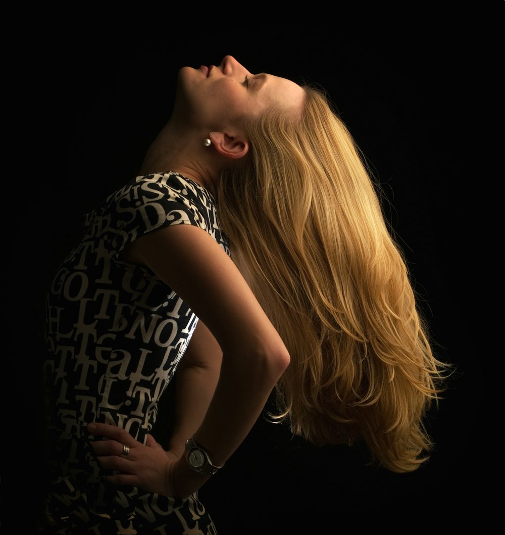 a woman with long blonde hair standing in front of a black background