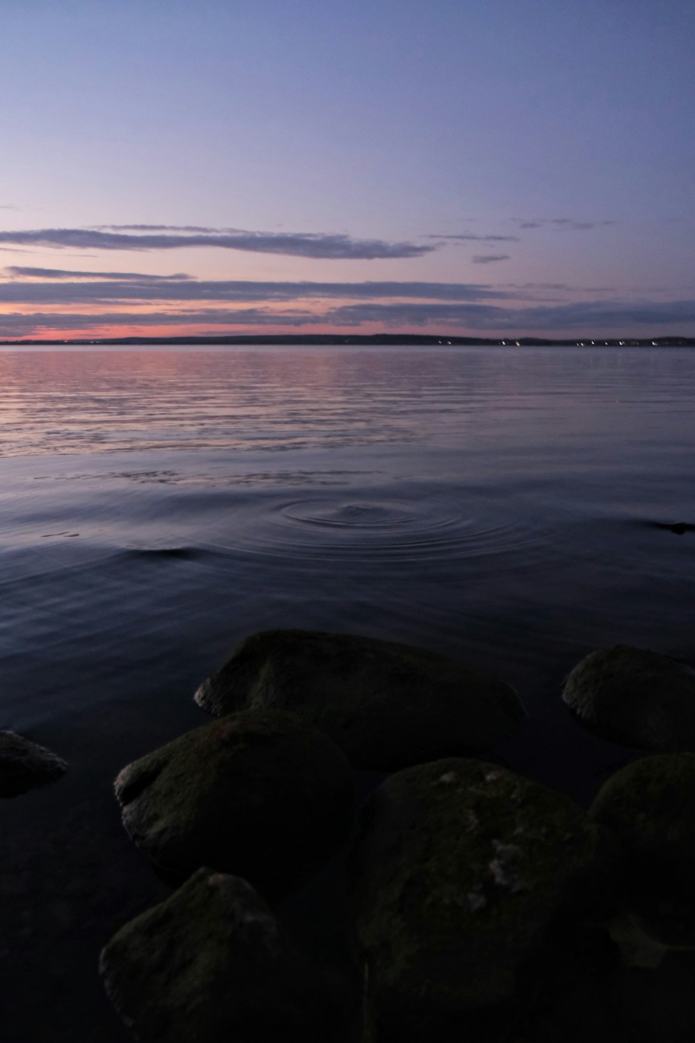 a body of water with rocks in the foreground