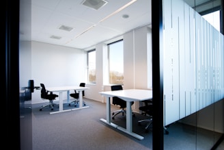 an office with a white table and black chairs