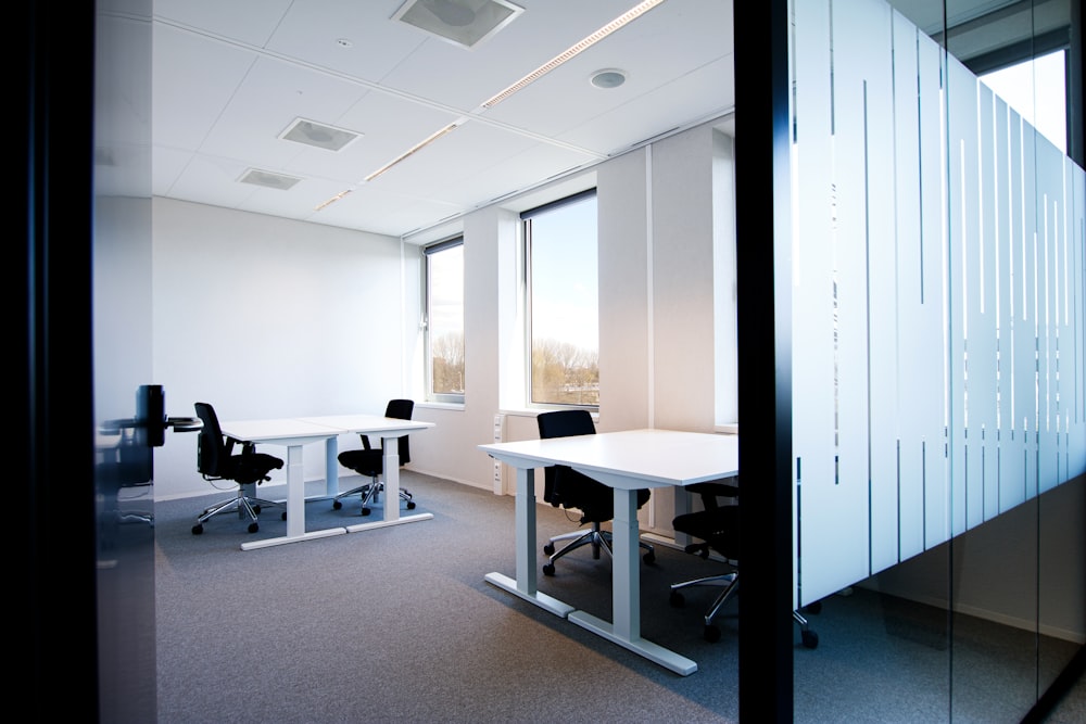 an office with a white table and black chairs