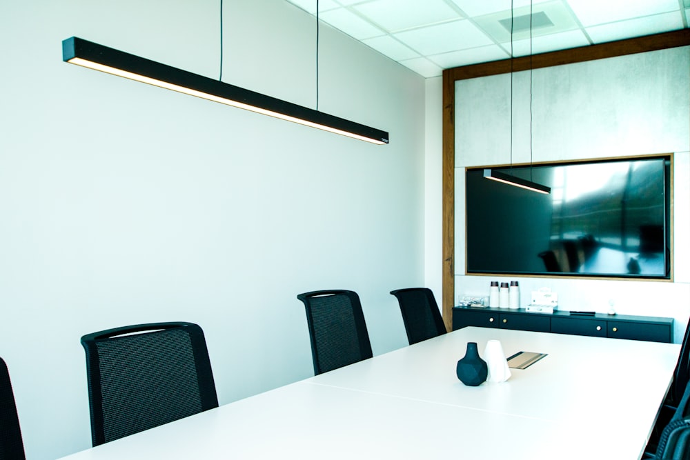 a conference room with a white table and black chairs