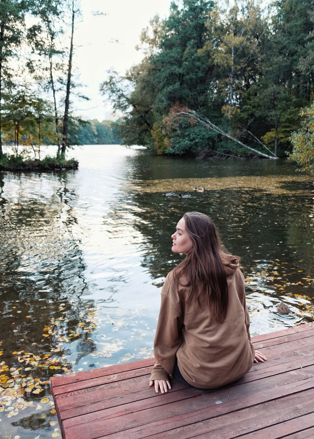 a woman sitting on a bench in front of a lake