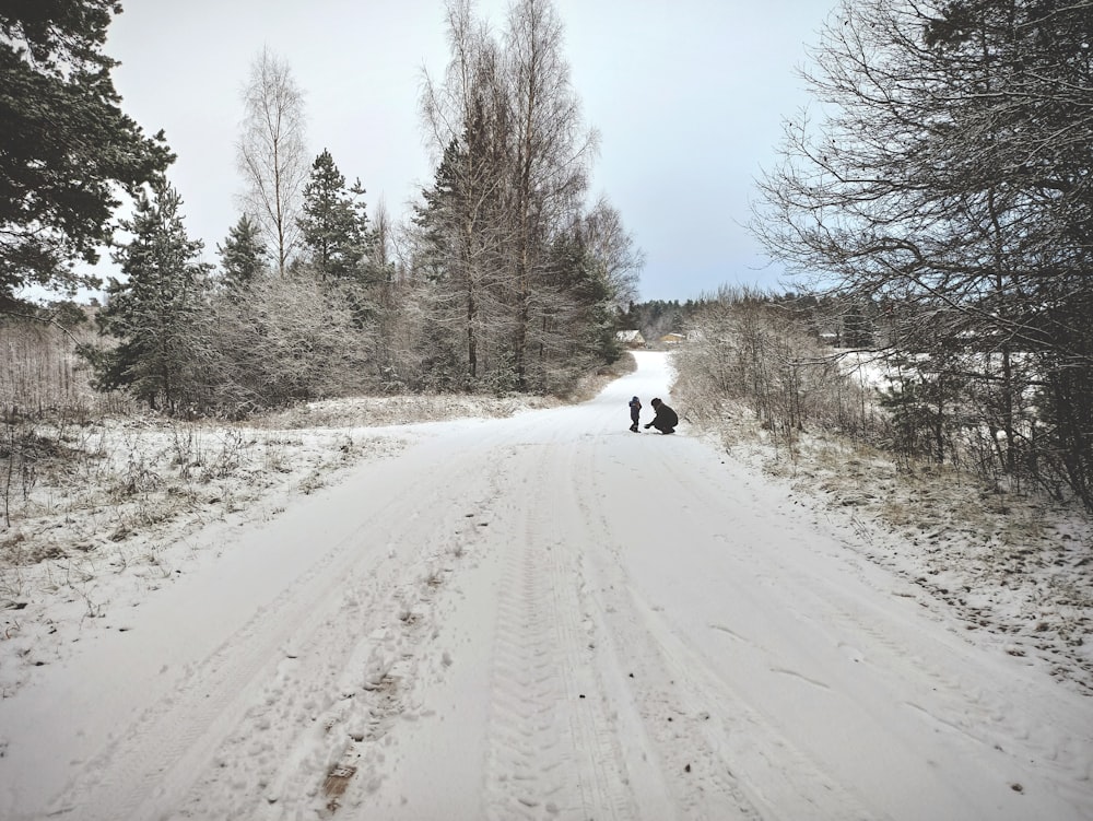 a couple of people riding on the back of a motorcycle down a snow covered road
