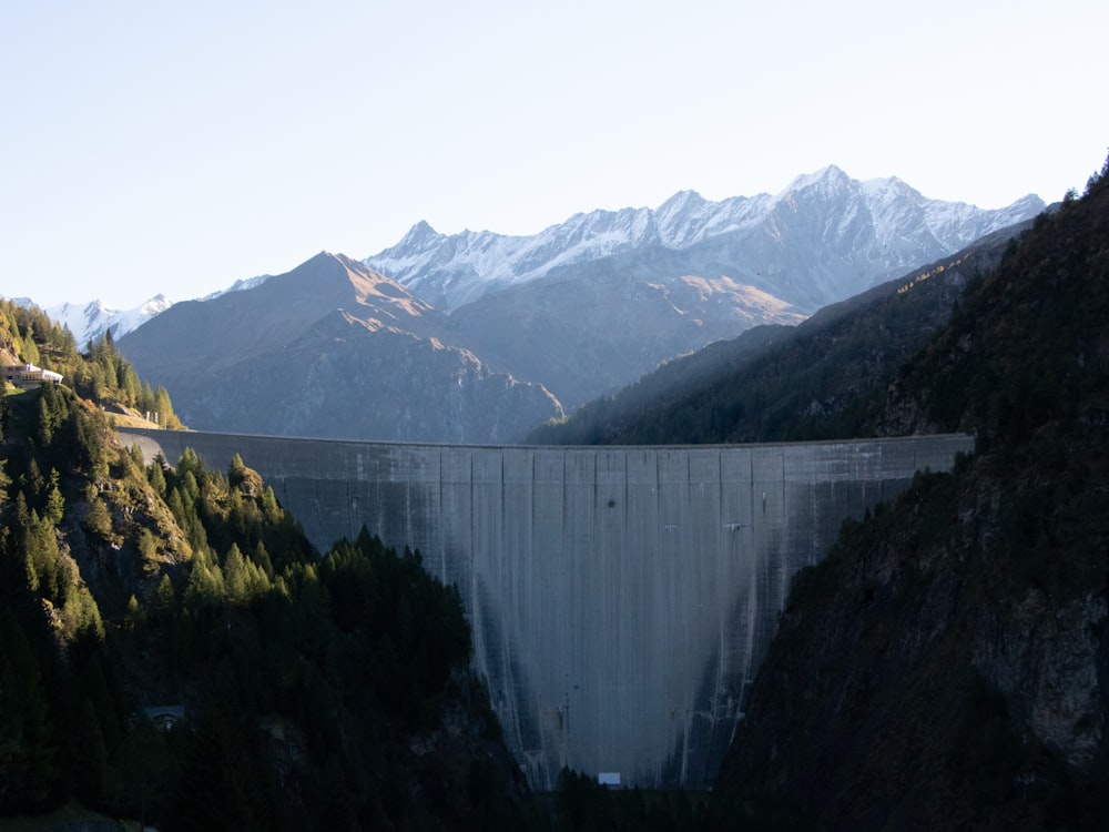 a large dam surrounded by mountains and trees