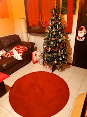 A cozy living room decorated for Christmas with a beautifully adorned tree and wrapped gifts.