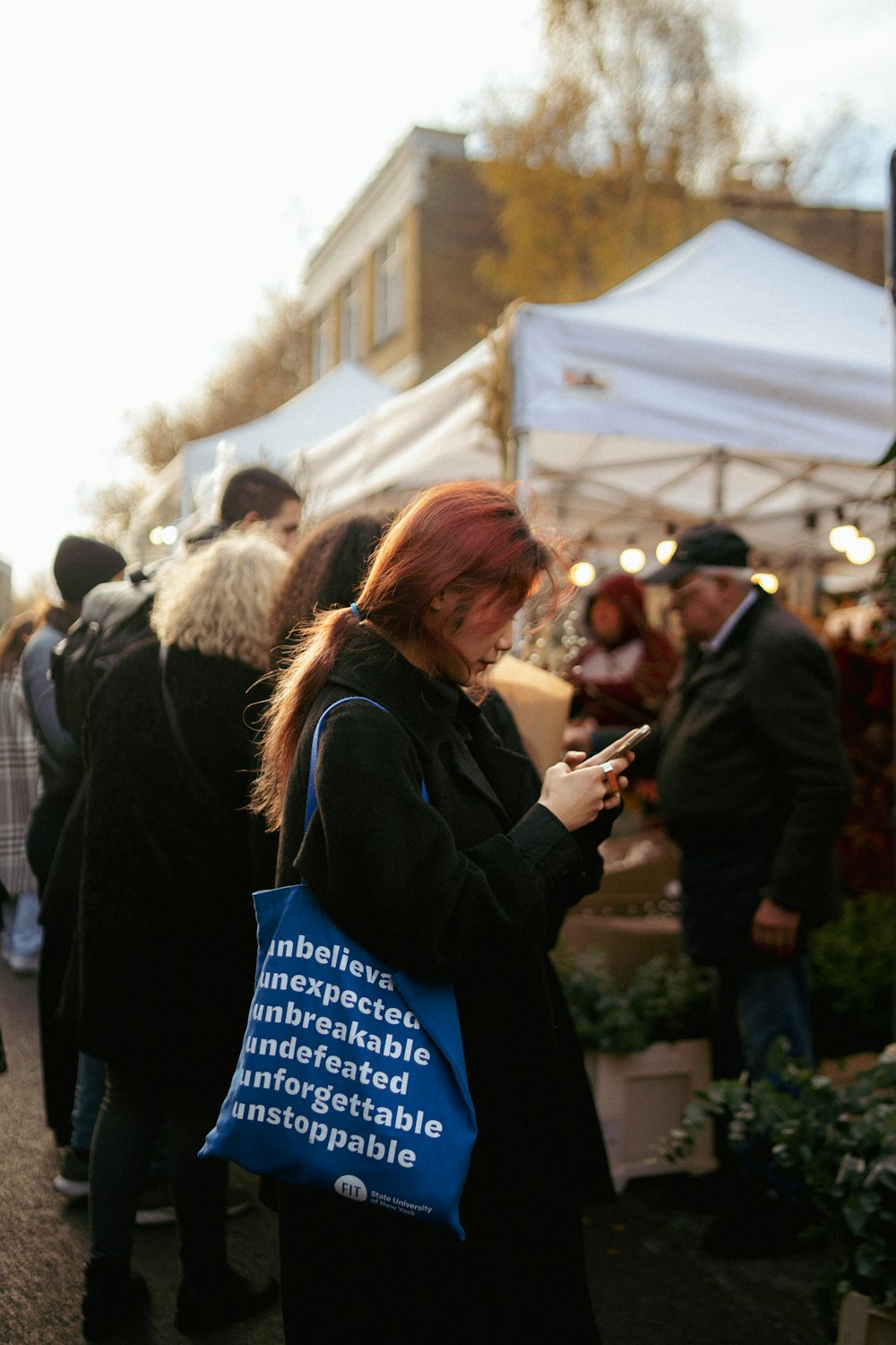 a woman with red hair is looking at her cell phone