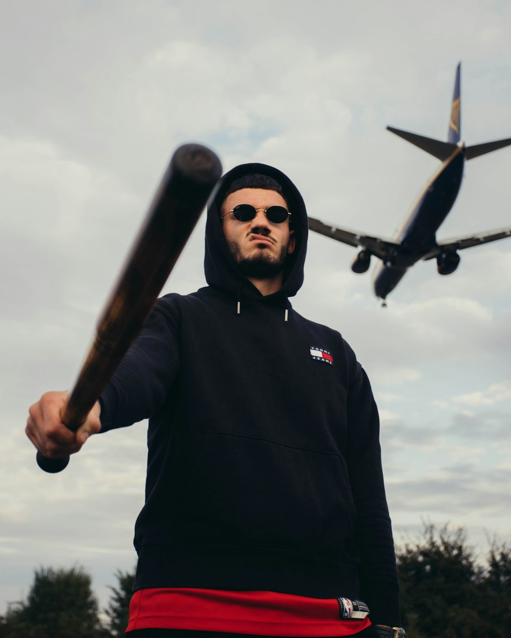 a man holding a baseball bat in front of an airplane
