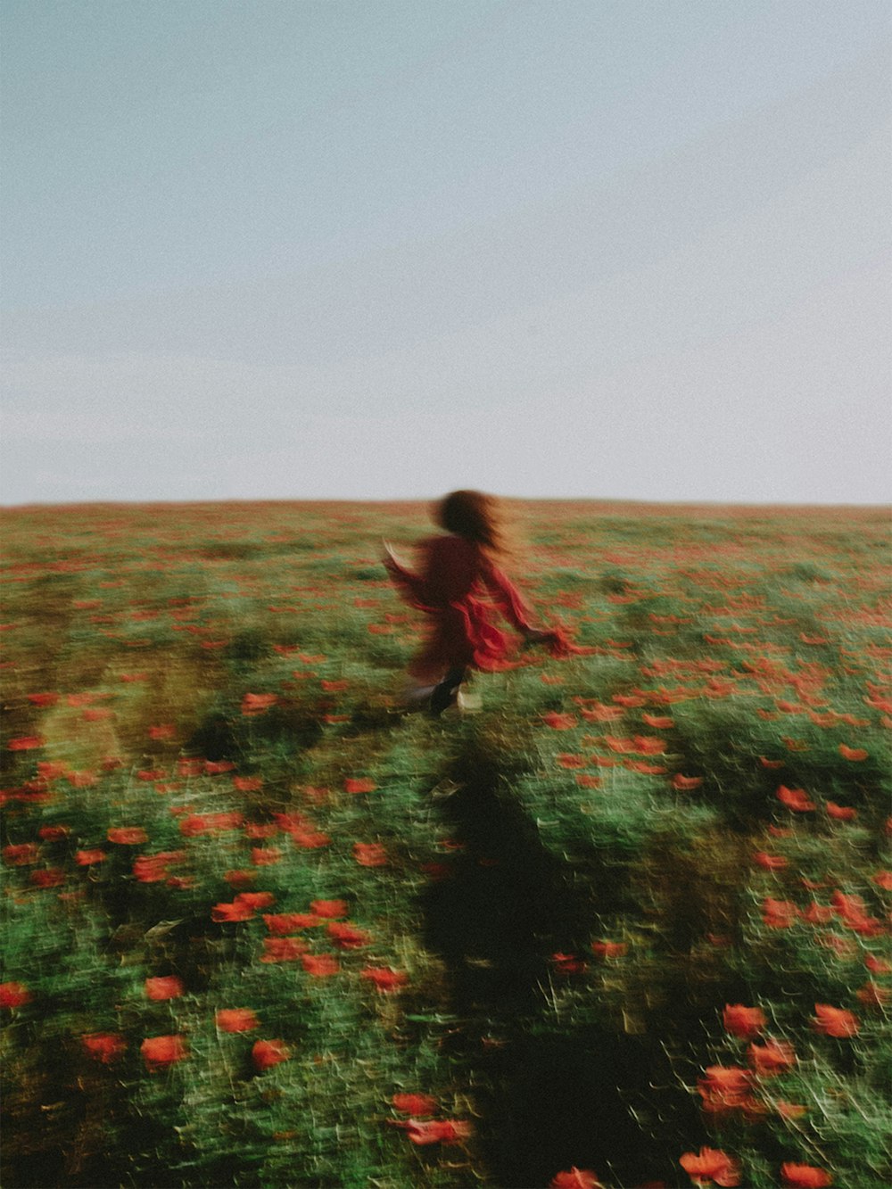 a woman running through a field of flowers