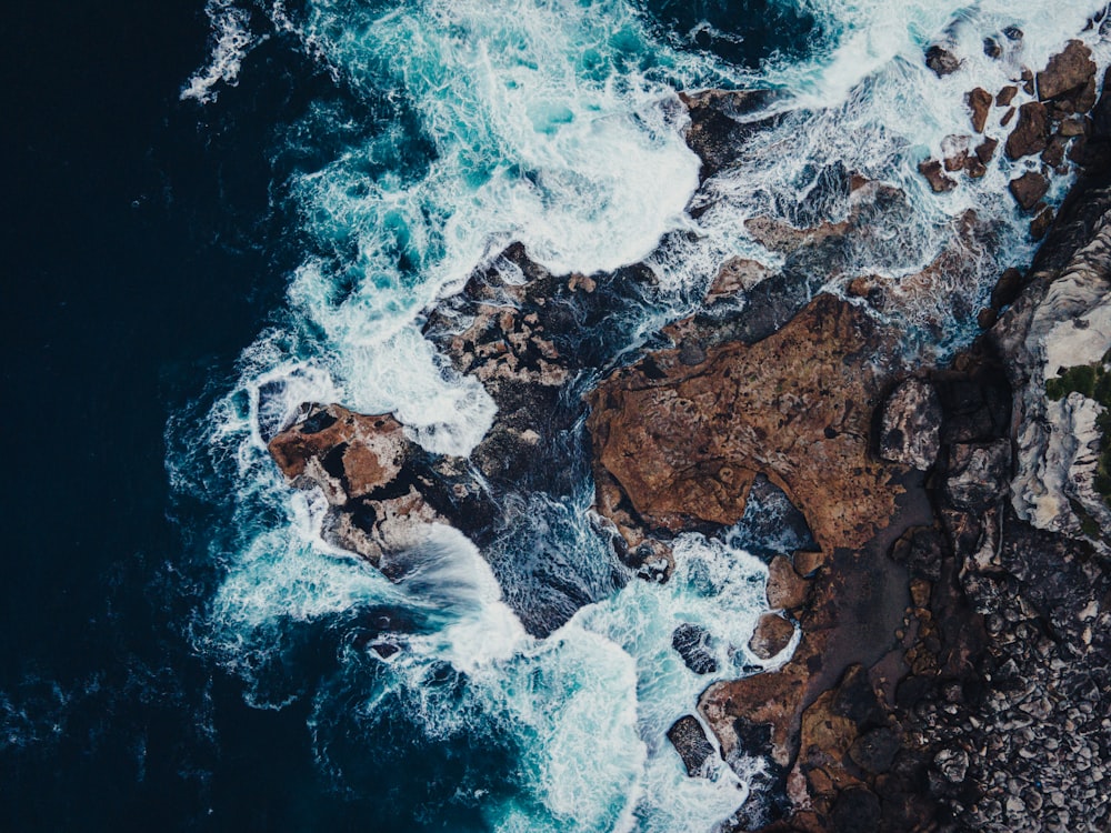 an aerial view of the ocean and rocks