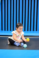 a little girl playing with a ball on the ground