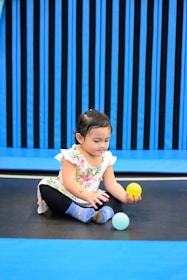 a little girl playing with a ball on the ground