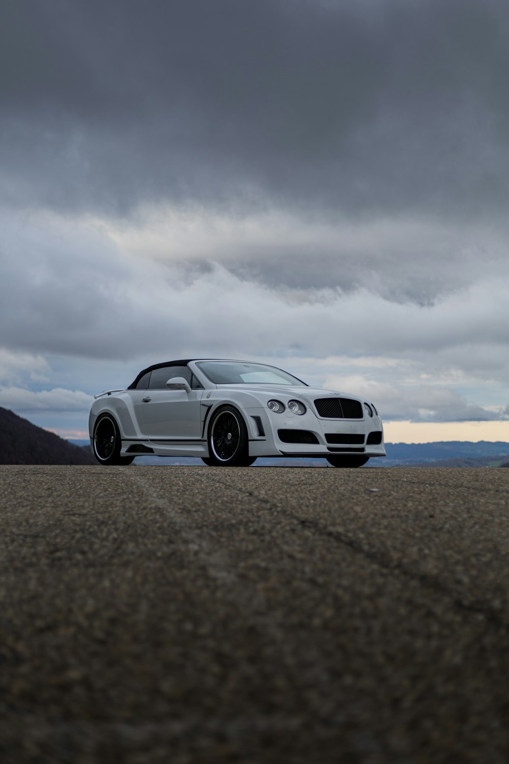 a white sports car parked on a road under a cloudy sky