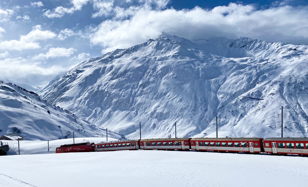 a red train traveling through a snow covered mountain