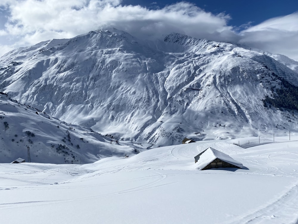 a snow covered mountain with a house in the foreground