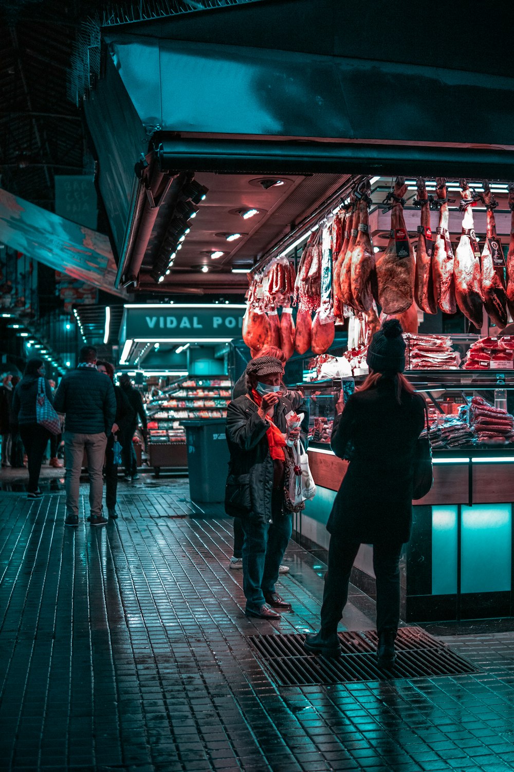 a group of people standing in front of a meat stand