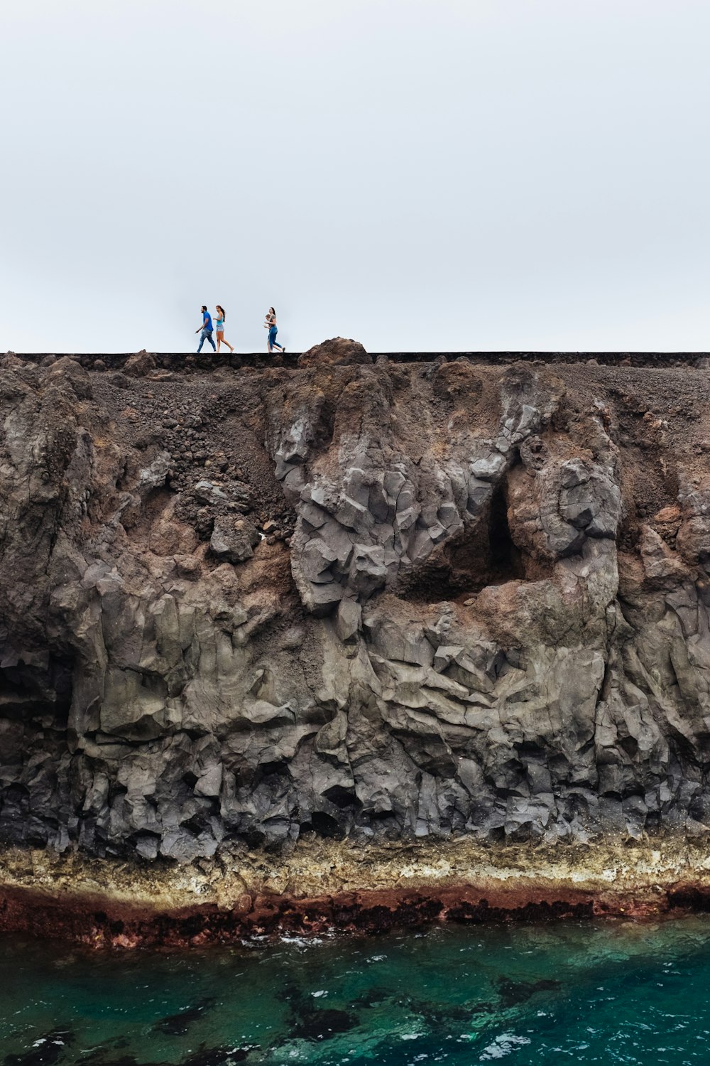 two people standing on a cliff above the ocean