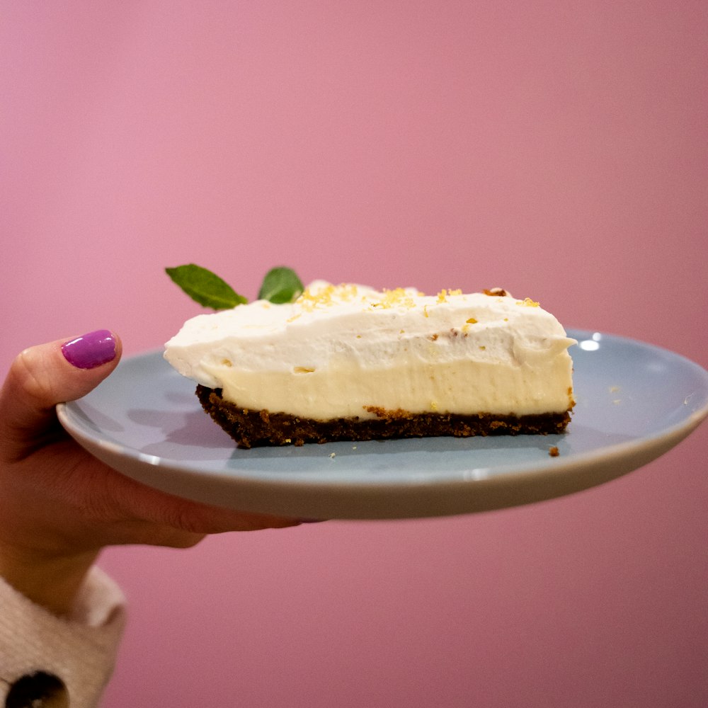 a person holding a piece of cake on a plate