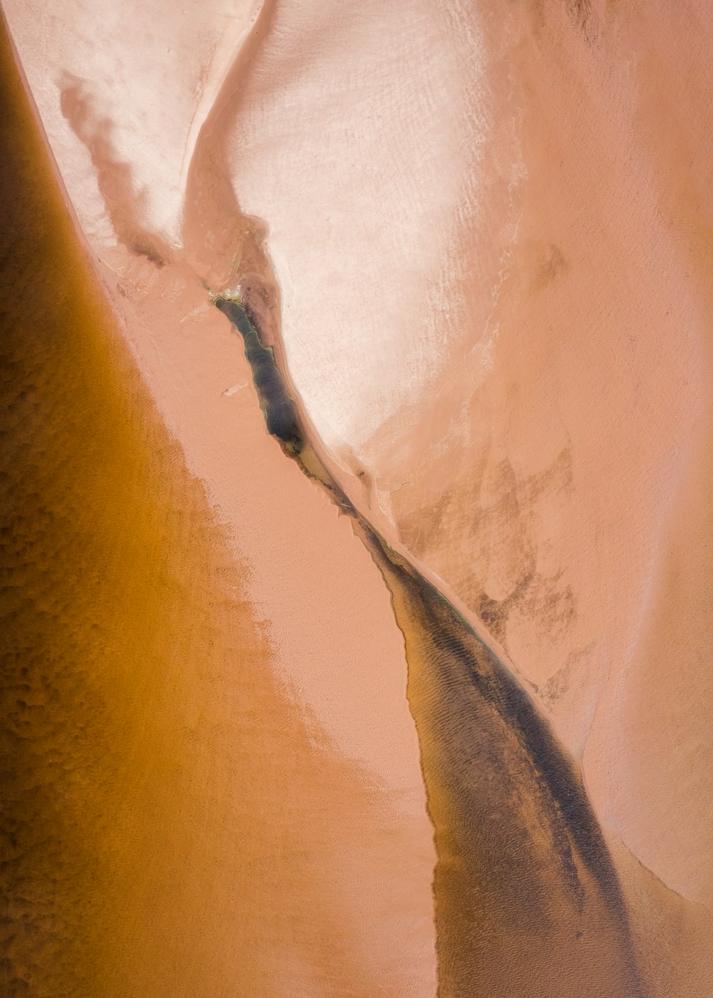 an aerial view of a sand dune with a stream running through it