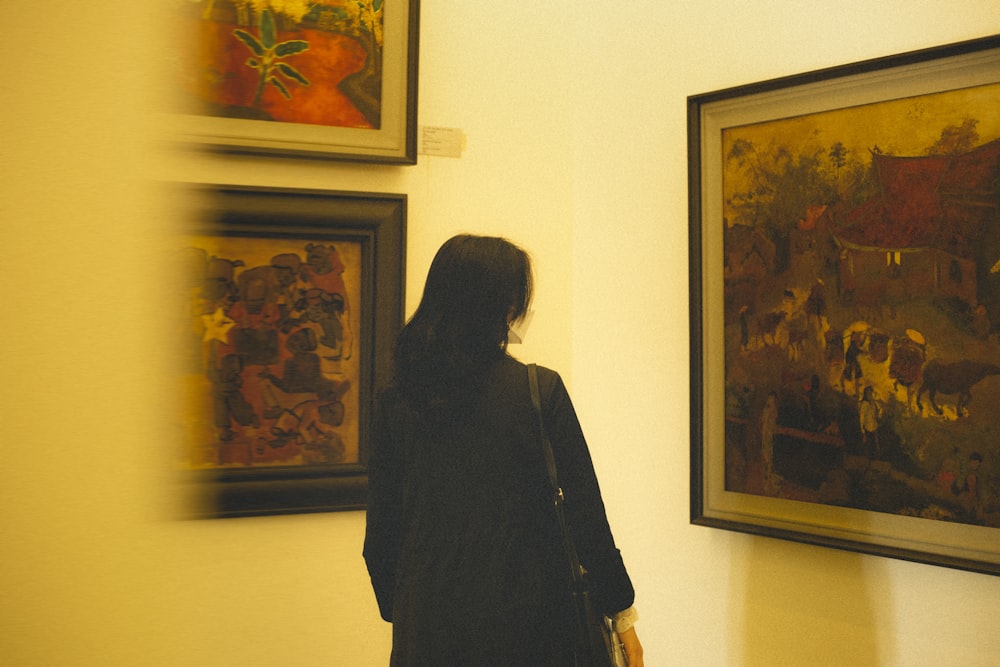 a woman standing in front of some paintings