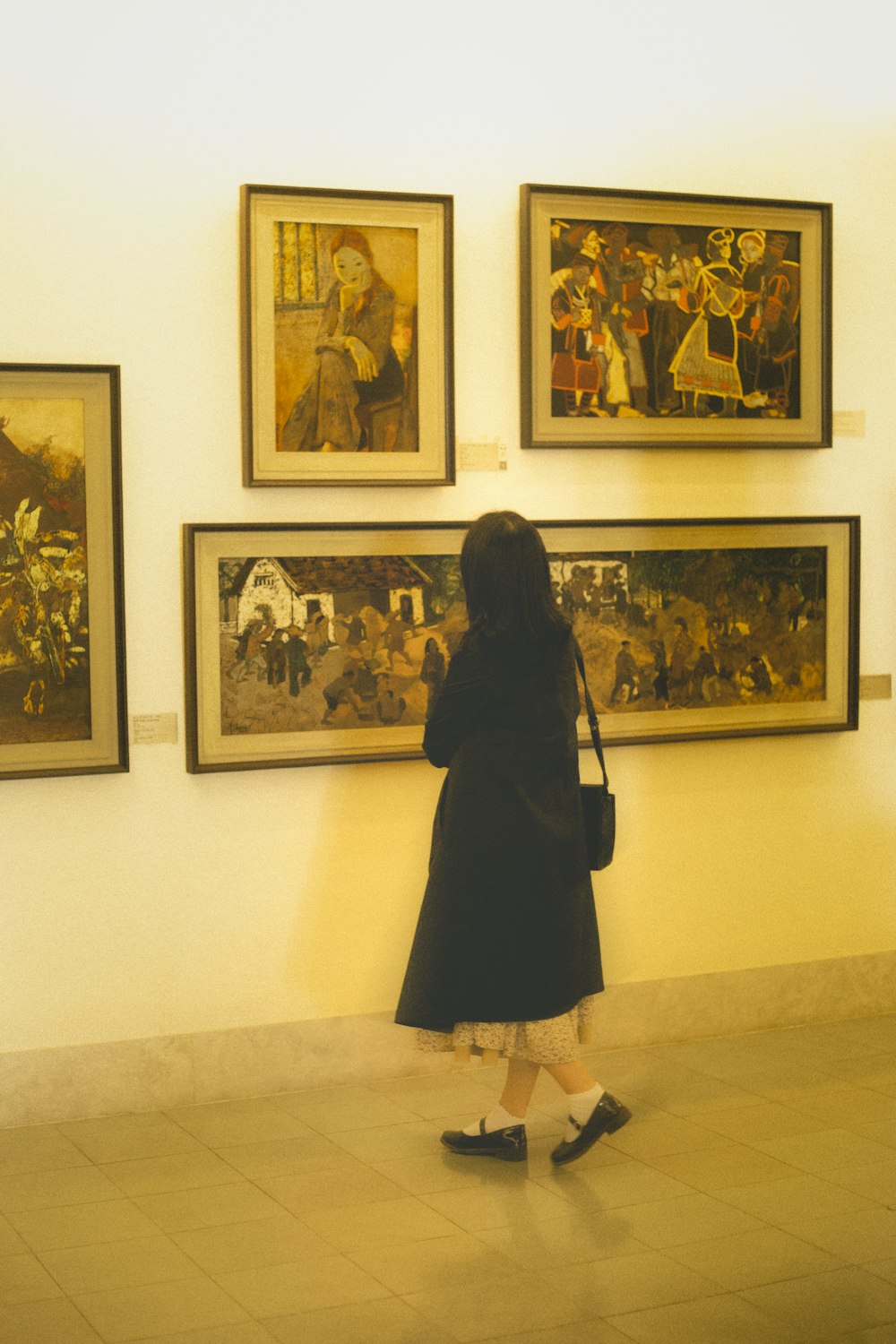 a woman looking at paintings on a wall