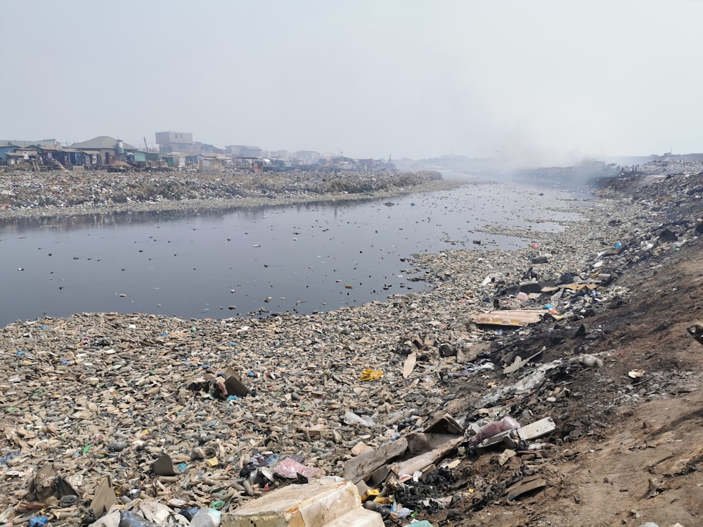 a large amount of trash is on the shore of a river