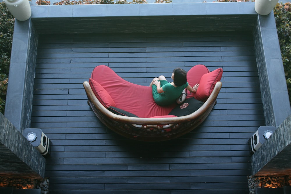 a person sitting on a red couch on a deck