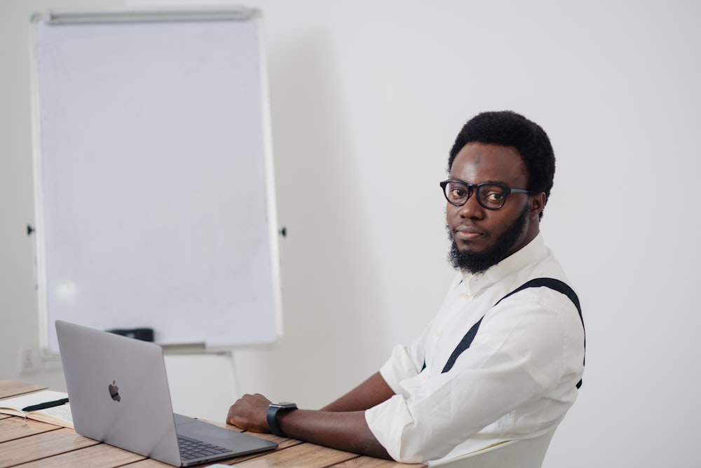 um homem sentado em uma mesa com um laptop na frente dele