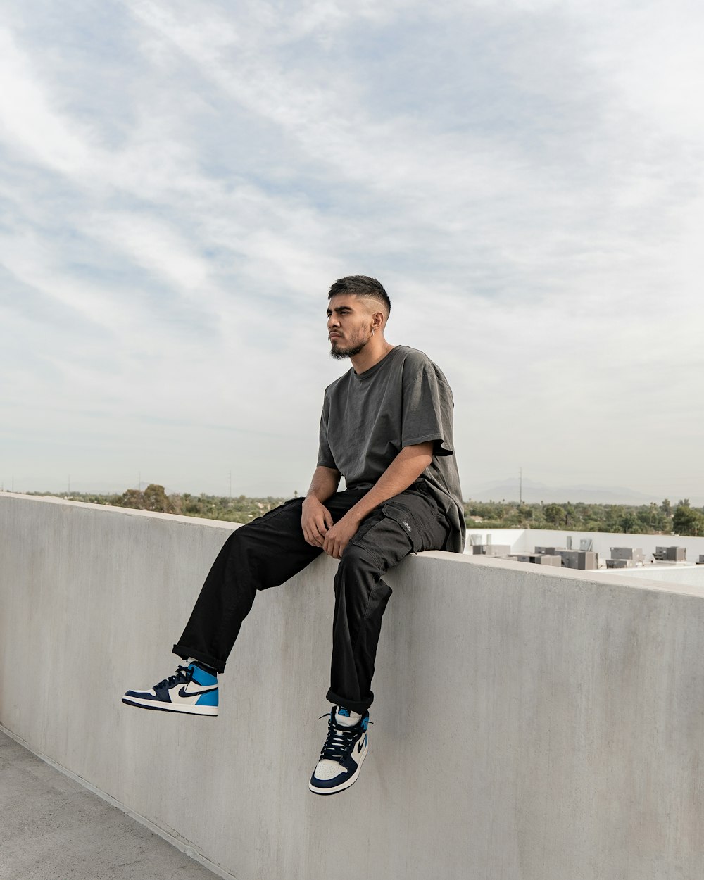 a man sitting on top of a cement wall