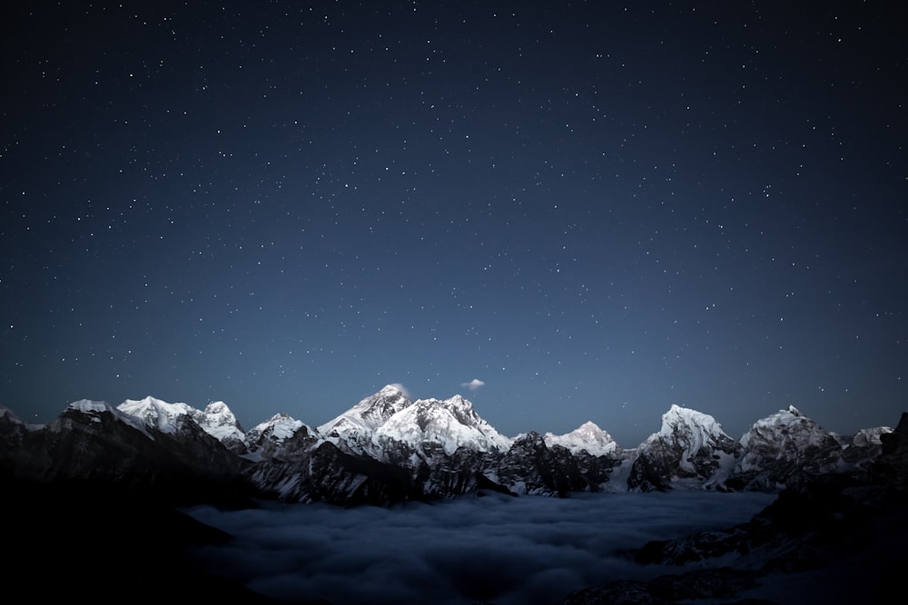 a night sky with stars above a mountain range