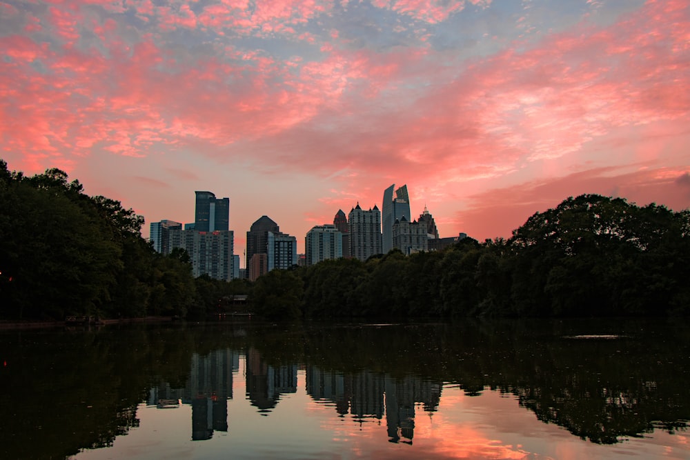 a city skyline is reflected in the still water of a lake