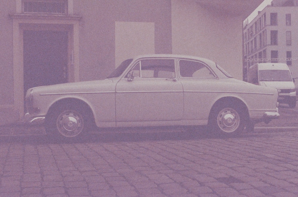 an old white car parked on a brick street
