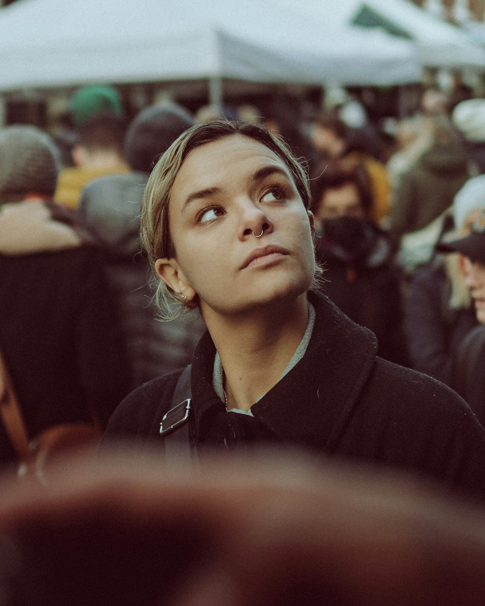 a woman looking up at the sky in a crowd of people