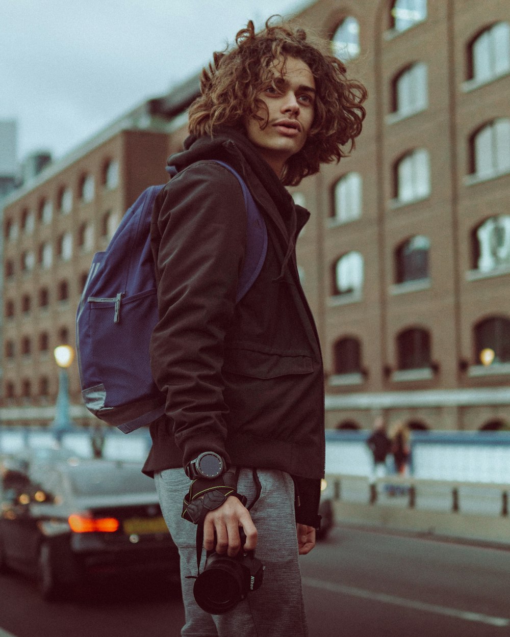 a man standing on the side of a road holding a camera