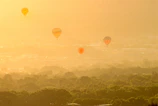 Drone shot capturing a fleet of emerald and gold balloons soaring above the Nile River’s winding curves.