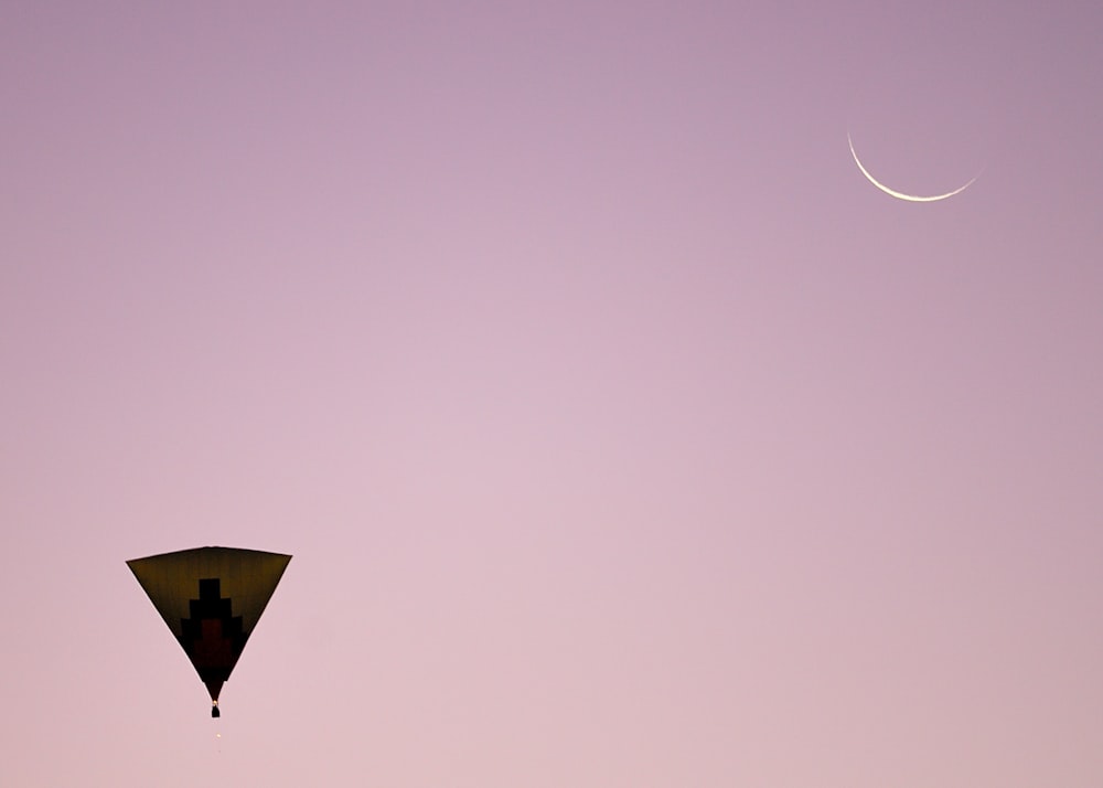 a kite flying in the sky with a crescent in the background